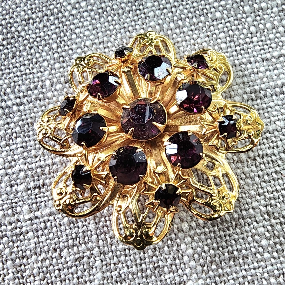 Vintage gold-toned round floral pin/brooch w/ deep violet rhinestones. 1960's